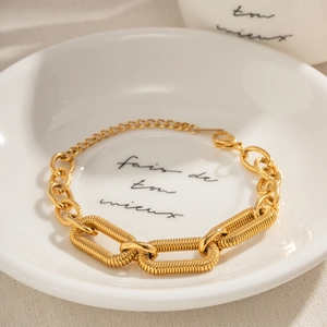 Detail of 18k gold chain bracelet with spiral texture on elegant white ceramic dish