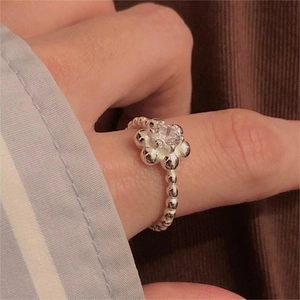 Macro view of a 925 sterling silver flower ring with zircon on a finger