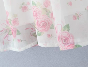 Detailed macro view of white floral dress hem with pink rose prints on chiffon fabric