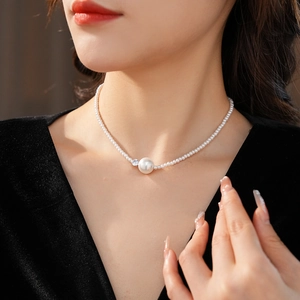 Dettaglio di elegante collana di perle con zirconi indossata da una modella con scollo a V