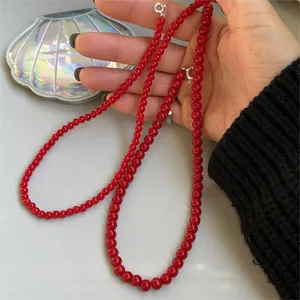Primo piano di una collana minimalista con perline rosse in argento sterling 925 in mano