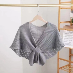 Detail of grey hollow-out knit shawl featuring a large bow on a wooden hanger
