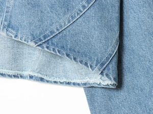 Makroansicht der blauen Denim-Struktur und der detaillierten Nähte am Saum der Jeansjacke