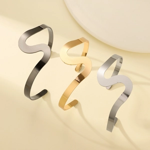 Vue détaillée de bracelets métalliques ondulés en noir, or et argent avec texture polie