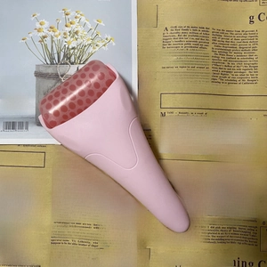 Detailed close-up of pink face ice roller on vintage newspapers for skin care routine