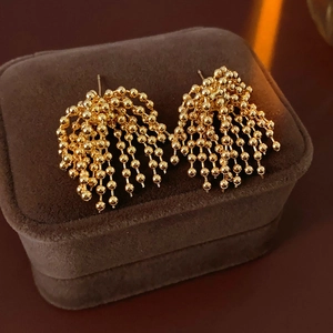 Detail of gold-plated firework tassel earrings on a premium brown velvet jewelry box