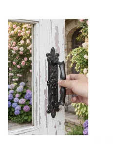 Close-up of black vintage cast iron handle with embossed base on a rustic wood door