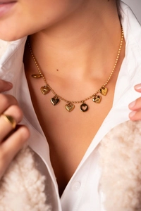 Detail of 18K gold plated ball chain necklace with diverse heart pendants on a model