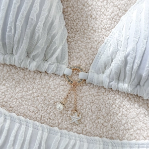 Detail of white textured bikini with gold rhinestone ring, pearl and starfish charm