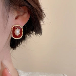 Detail of vintage gold-rimmed resin earrings with red oval inlay and center pearl