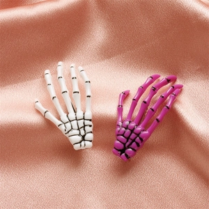 Detail of Gothic skeleton hand hair clips in white and purple on silk background