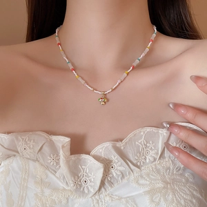 Close-up of a colorful beaded necklace with a golden mushroom pendant on a model