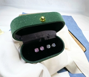 Close-up of classic 4-prong silver stud earrings in purple and clear stones