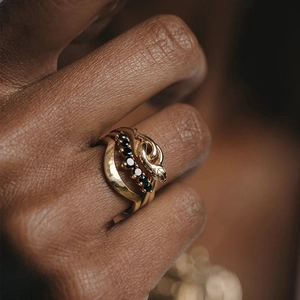 Detailed close-up of a golden snake ring set with black stones and hammered texture