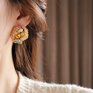 Détail de boucle d'oreille vintage dorée avec perles et cristaux jaunes sur le mannequin