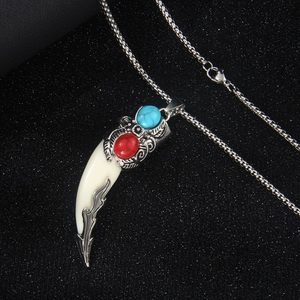 Ethnic wolf tooth pendant necklace with red and blue gems on a silver chain
