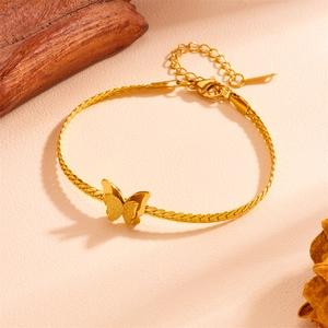 Detail of a golden butterfly pendant on a curb chain with matte and glossy finishes