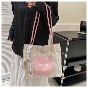 Détail d'un sac cabas en paille avec poche rose et foulard sur l'anse tressée
