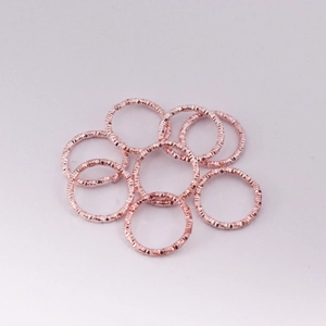 Vista dettagliata di anellini aperti in oro rosa con texture martellata per gioielli DIY