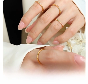Macro detail of four stacked 18k gold plated titanium rings with colorful rainbow stones