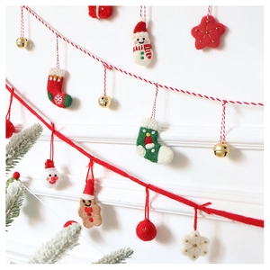 Detailed view of handcrafted wool felt Christmas ornaments hanging on a red and white string