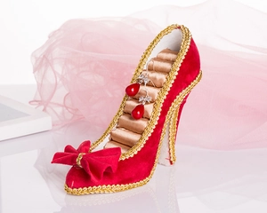 Detail of red velvet high heel jewelry stand featuring gold trim and ring storage slots