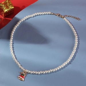Christmas pearl necklace with red bell pendant and bow decoration on textured background
