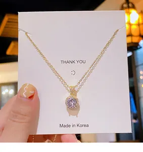 Détail d'un collier doré avec pendentif halo en zircon sur une carte cadeau