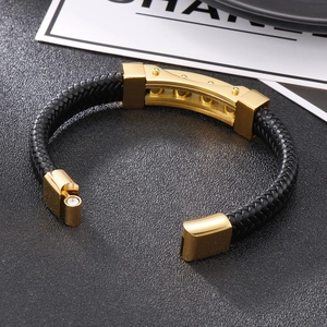 Detail of black braided leather bracelet with polished gold-tone magnetic clasp