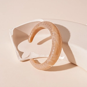 Detailed close-up of C-shaped resin bangle with pink marble texture and knotted design