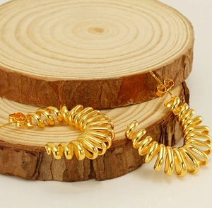 Detail of 18k gold plated spring hoop earrings on rustic wooden display blocks