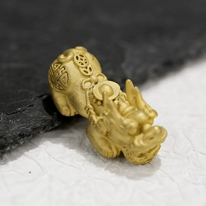 Macro view of 18K gold plated stainless steel PiXiu charm with relief texture
