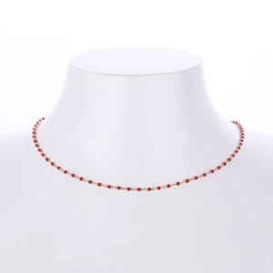 Close-up of a gold s925 silver necklace with small red beads on a white mannequin
