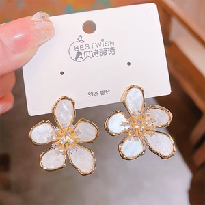 Macro shot of 5-petal flower stud earring with shell texture and shimmering zircon core