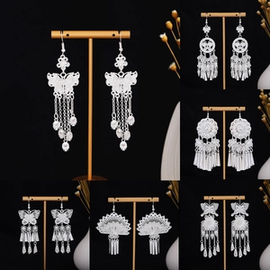 Dettaglio di sei orecchini etnici in argento con nappe e motivi floreali a farfalla