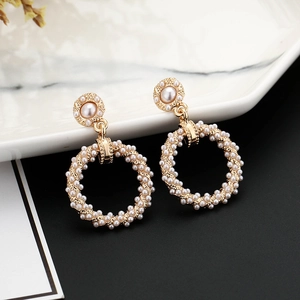 Close-up of gold hoop earrings featuring elegant white pearls on a white marble display