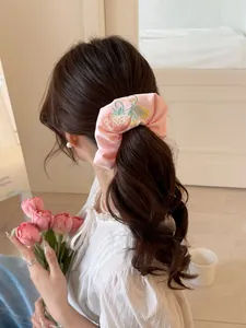 Detail of pink satin scrunchie with strawberry embroidery worn in a ponytail