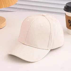 Close-up of a plain off-white cotton baseball cap on a desk with warm ambient lighting