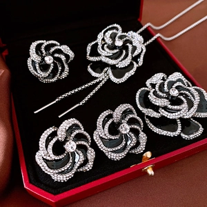 Detail showing black enamel camellia jewelry set with crystals in red velvet box