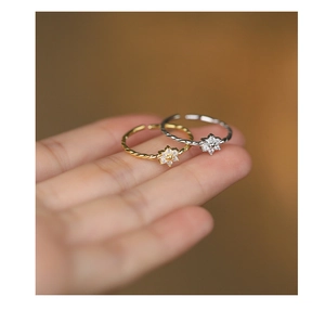 Detail of twisted rope band ring with micro-pave zircon flower in gold and silver finish