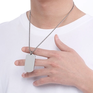 Close-up of a silver rectangular stainless steel dog tag necklace with a bead chain