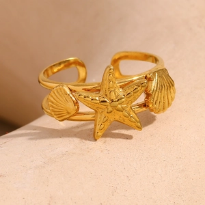 Macro shot of gold starfish and shell open ring with dual-line band on stone background