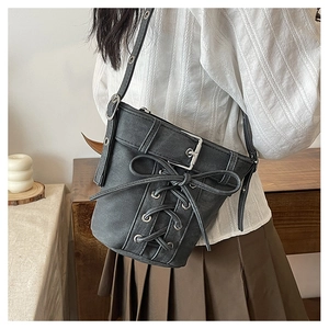 Détail du sac seau en toile noire avec design corset à lacets et œillets sur le mannequin