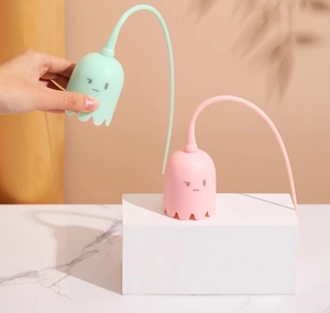 Detail of mint green and pink ghost-shaped cat toys with flexible long tails on marble