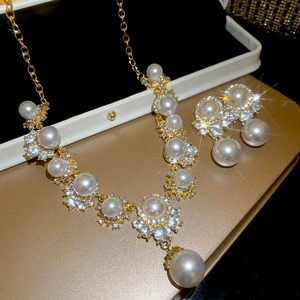 Close-up of golden necklace and earrings set with white pearls and sparkling crystals