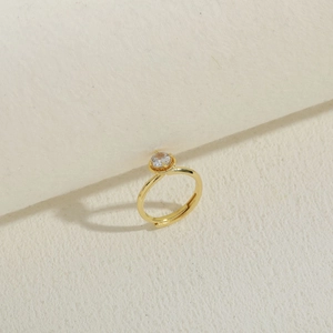 Detailed view of gold plated ring with a four-prong set round zircon and adjustable band