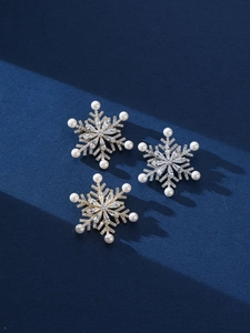 Detailed view of snowflake brooch with clear crystals and pearls on blue texture