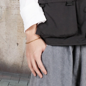 Close-up of a minimalist golden stainless steel O-link chain bracelet on a model's wrist