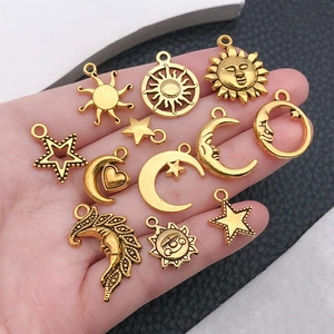 Makroaufnahme verschiedener goldener Himmelsanhänger für DIY-Schmuck in der Hand