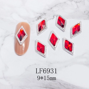 Vista macro de joyas para uñas rombo rojo 9x15mm con marco plateado sobre fondo de mármol
